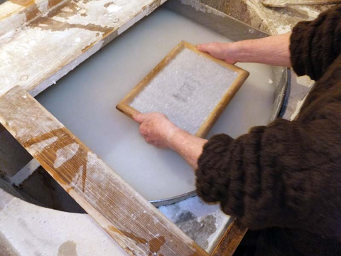 personne fabricant une feuille de papier à la main